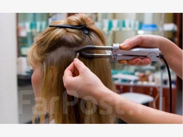 мастер в салоне снимает капсулы с волос клиента