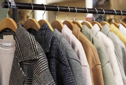 разные виды курток на вешалках в магазине